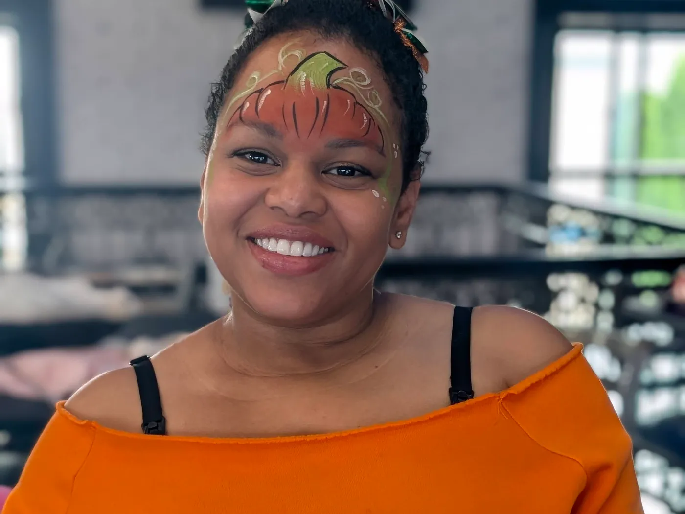 A smiling guest wearing an orange pumpkin face design
